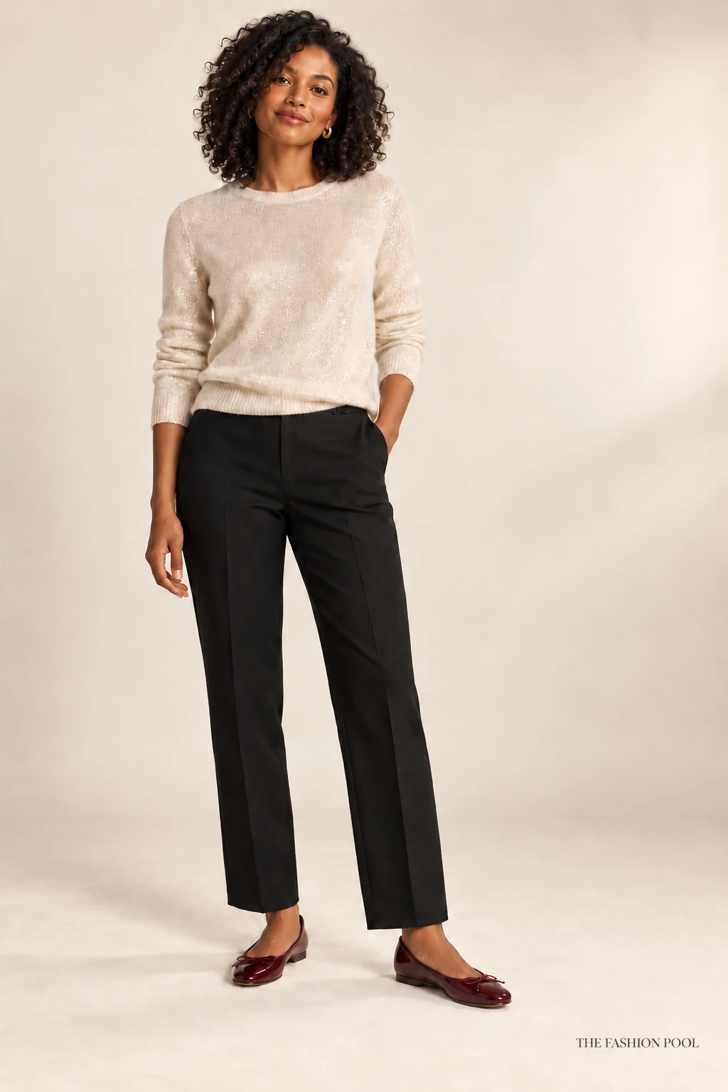Woman wearing a cream shimmer sweater, black straight-leg trousers and burgundy ballet flats.