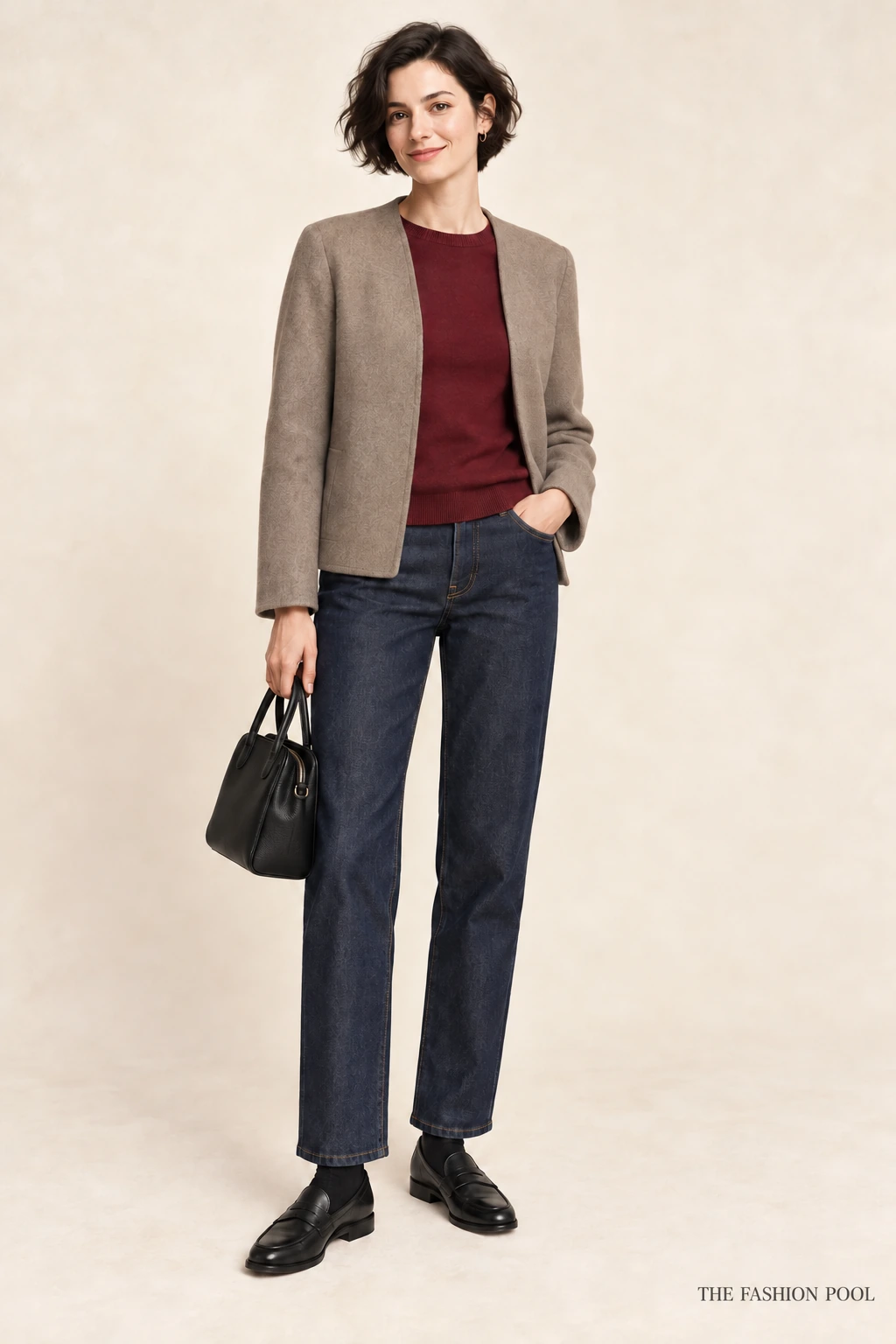 Woman illustrated in a burgundy sweater, taupe collarless jacket, dark straight jeans, black socks and loafers, holding a black bag.